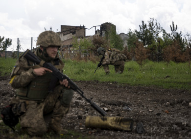 Ukrainian servicemen squat during a patrol in a recently retaken village, north of Kharkiv.